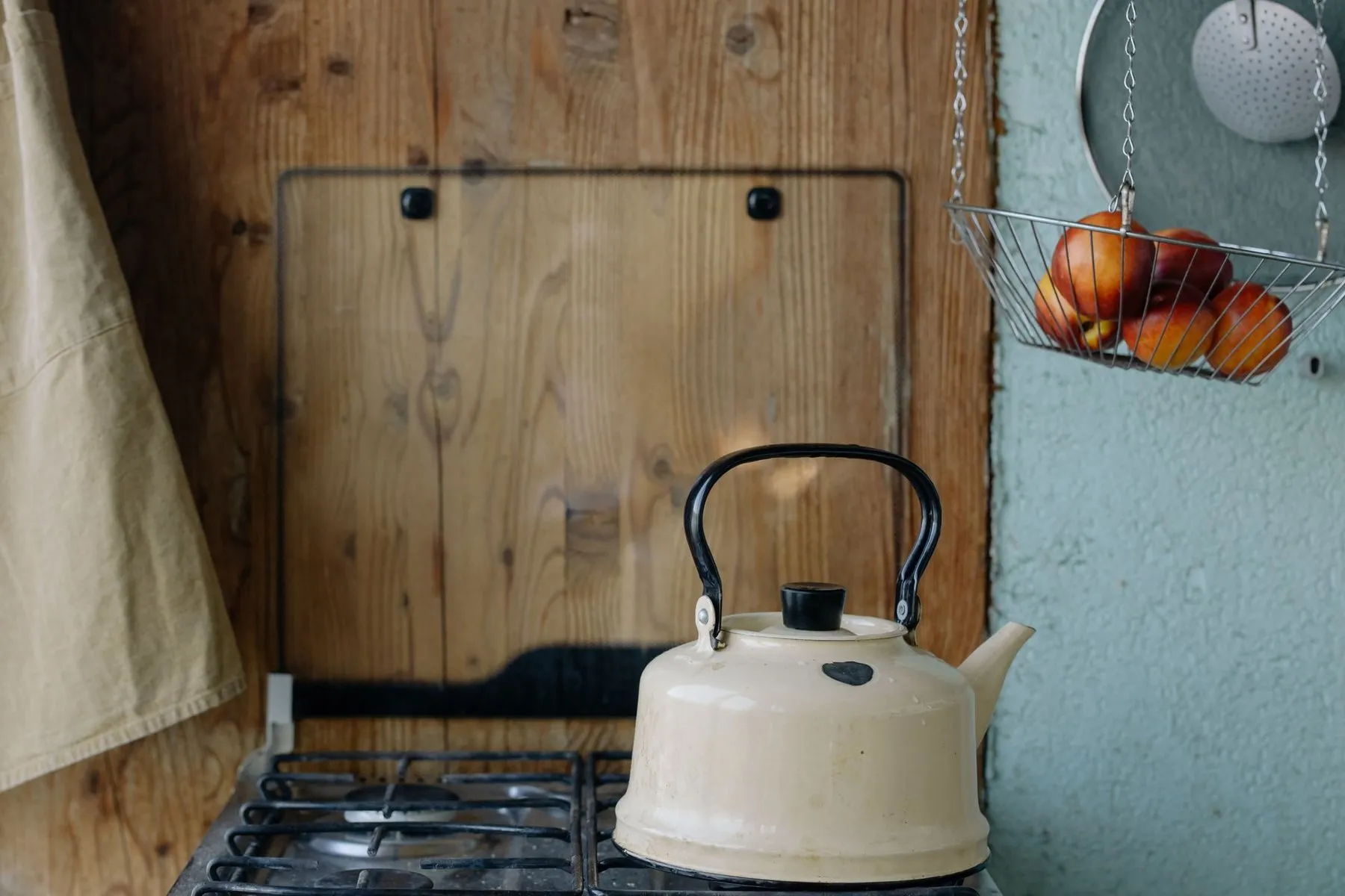 Cream enamel kettle on a gas hob in a wood-panelled kitchen