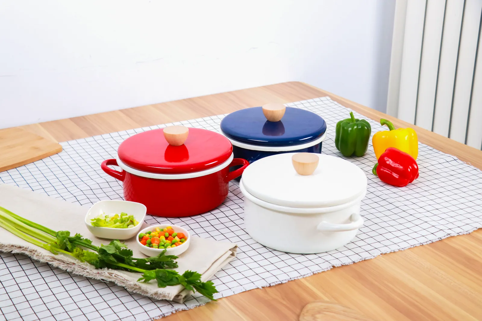 Three enamel pots with colourful lids on a workbench