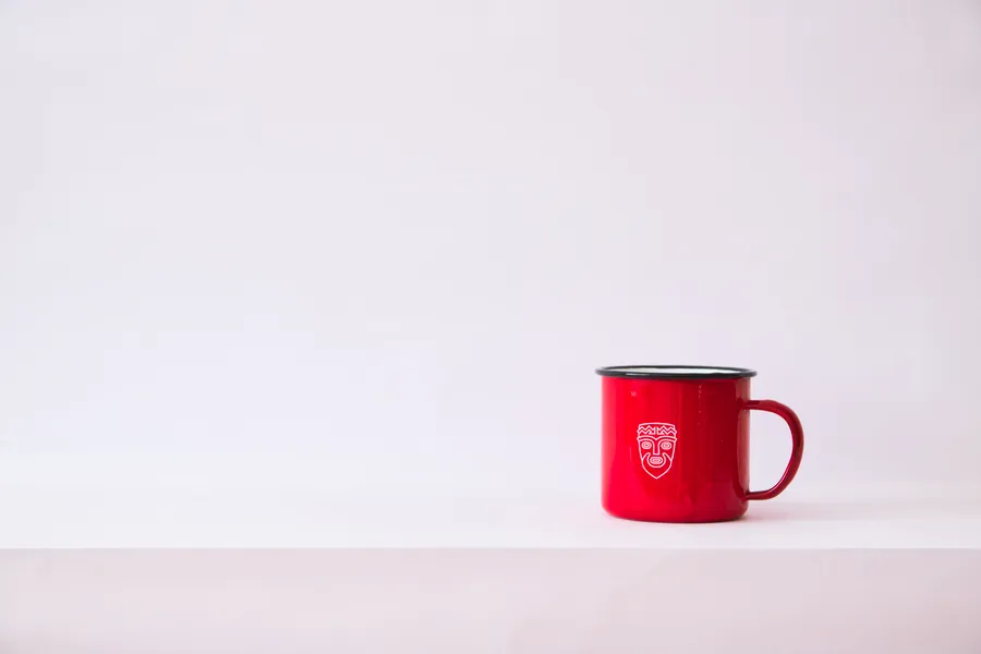 A red enamel mug on a plain white background